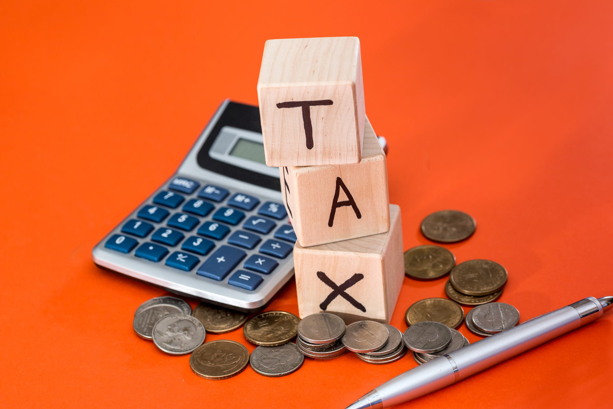 wooden cubes with text tax, coin and calculator isolated on orange